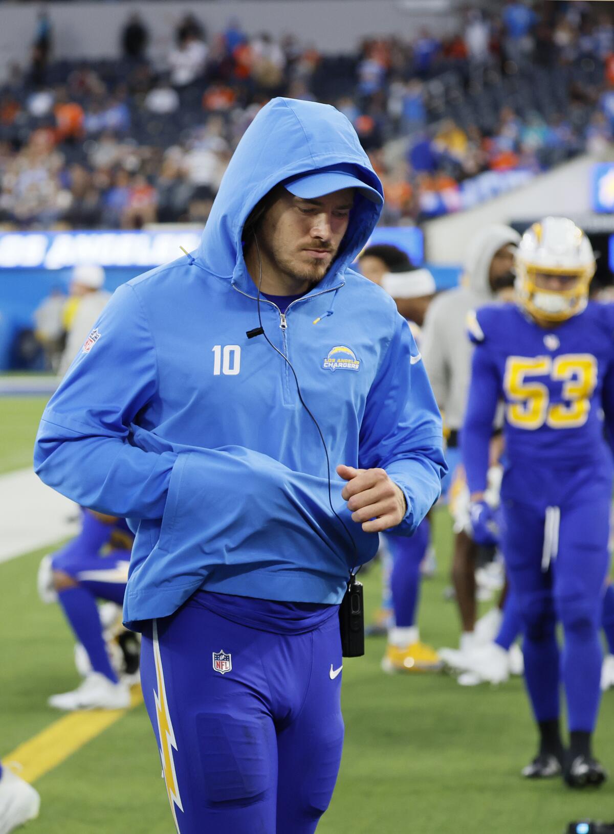 Chargers quarterback Justin Herbert walks off the field with an injured finger protected in his sweatshirt pouch.