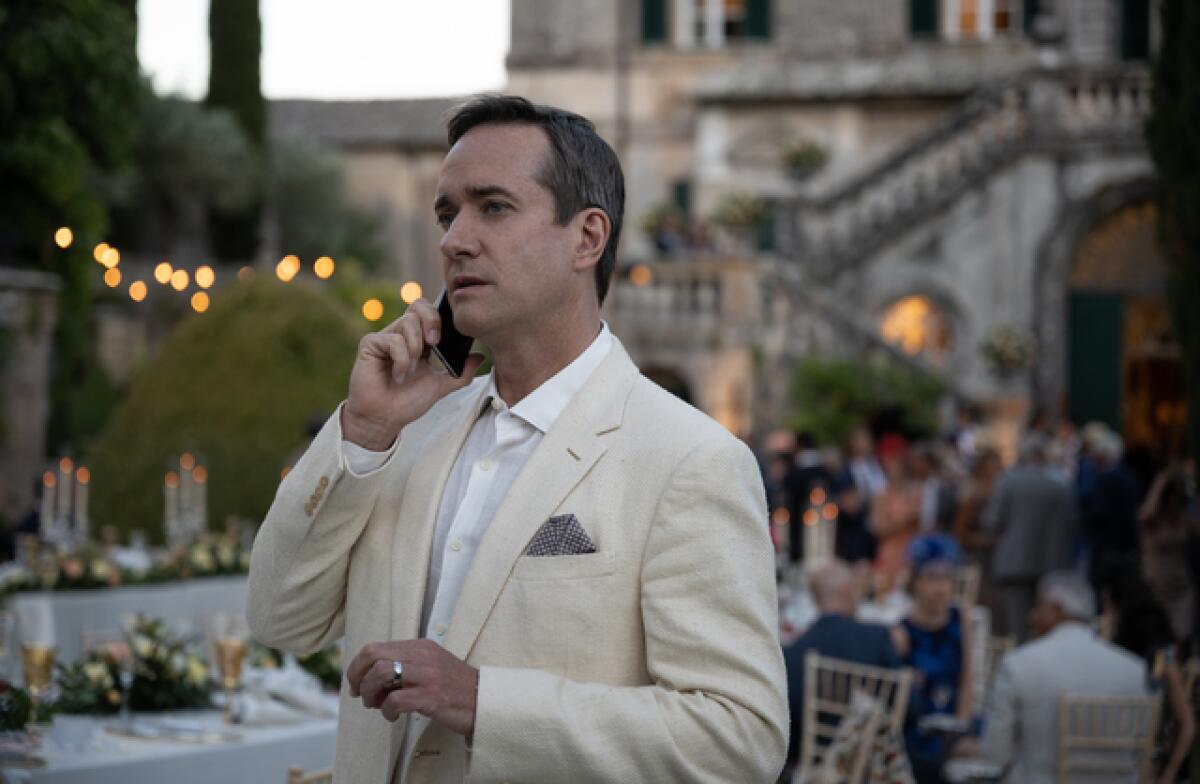 A man in a linen suit talks on the phone at a Tuscan villa wedding in a scene from "Succession."