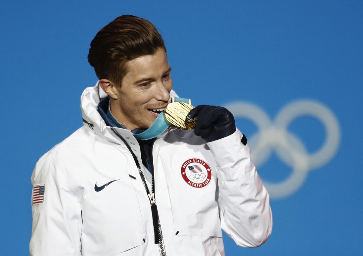 Shaun White bites a medal at the 2018 Olympics.