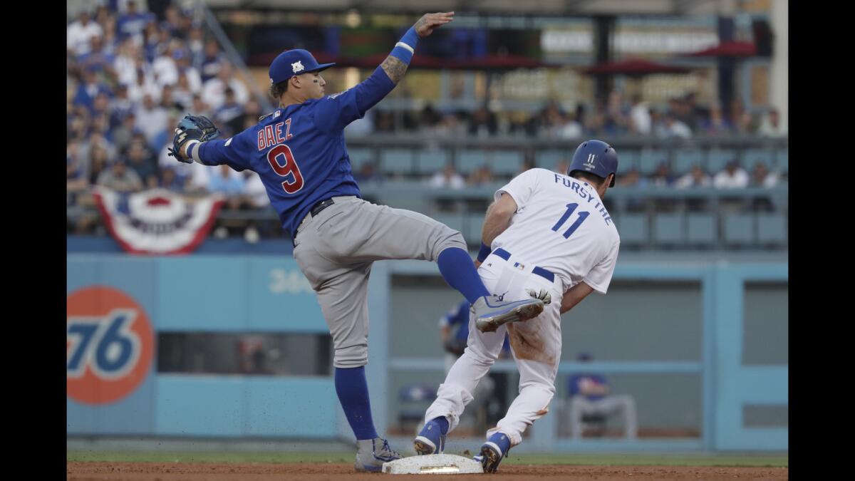 Cubs Javier Baez contorts his body to get out of a sliding Logan Forsythe as he completes the double play.