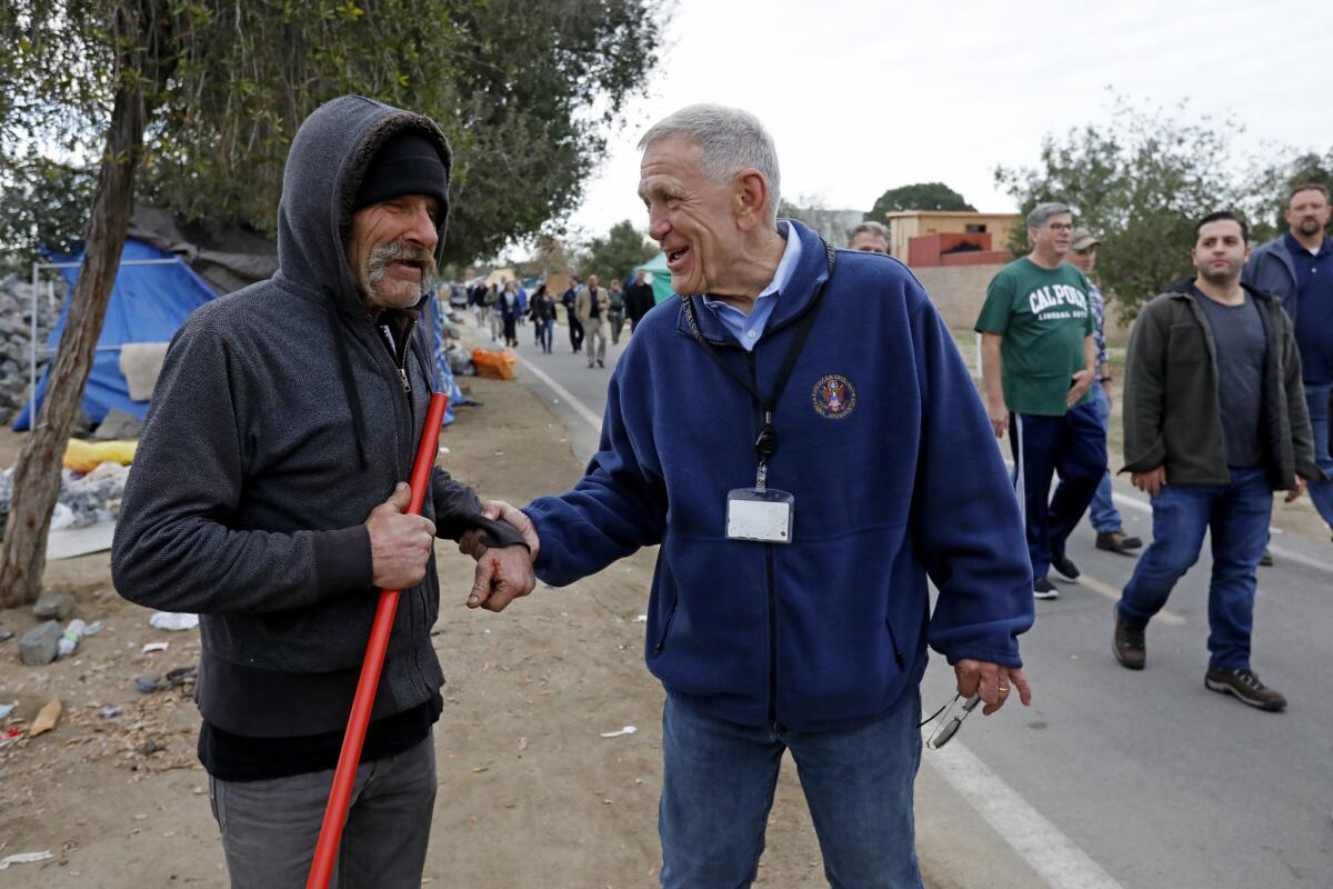U.S. District Judge David O. Carter, right, greets a homeless man while surveying an encampment in 2018 along the Santa Ana River in Anaheim. The area has since been cleared.
