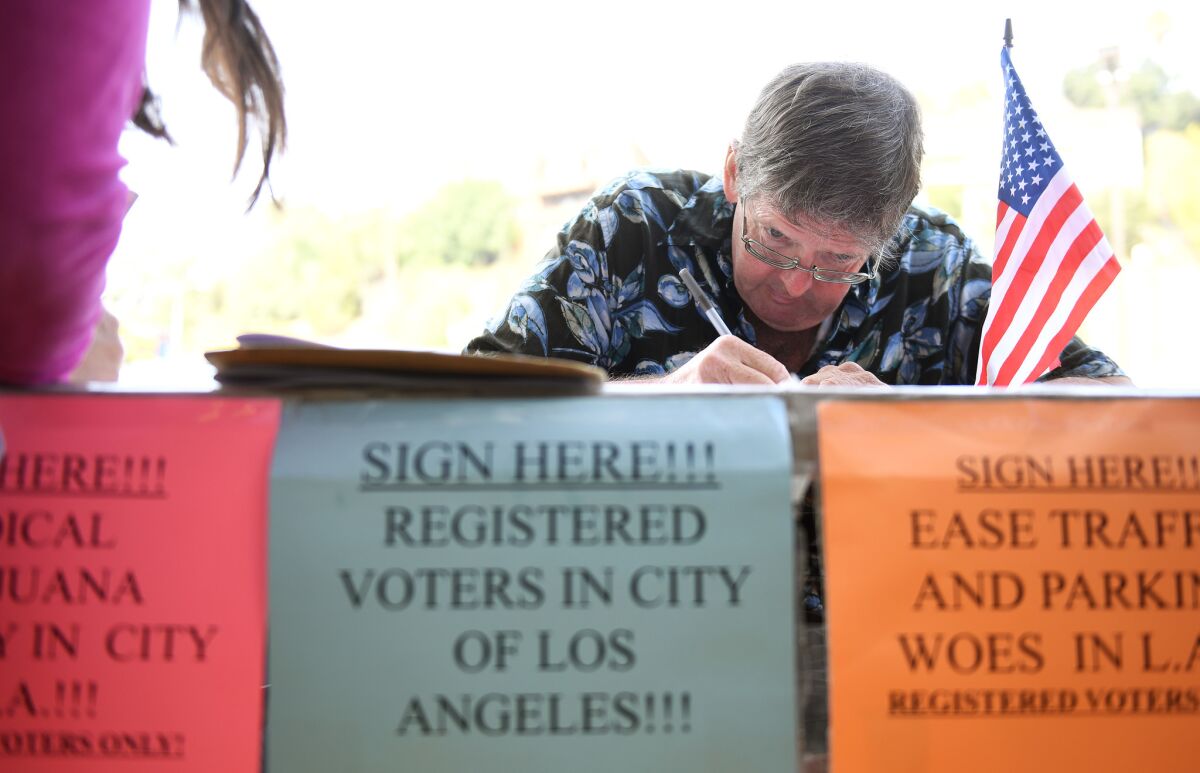 Tim Ecker collects signatures outside a grocery store in Silver Lake in August. (Christina House / Christina House)