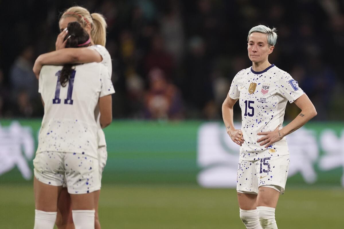 The United States' Megan Rapinoe watches her teammates hug after being eliminated from the World Cup 