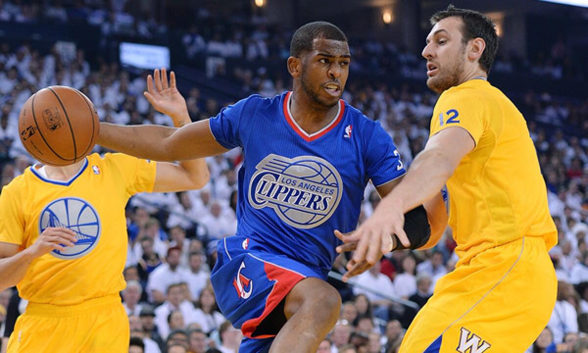 Clippers point guard Chris Paul, left, looks to pass around Golden State Warriors center Andrew Bogut during the Clippers' Christmas Day loss. Paul likely will not return from a separated shoulder injury until mid-February.