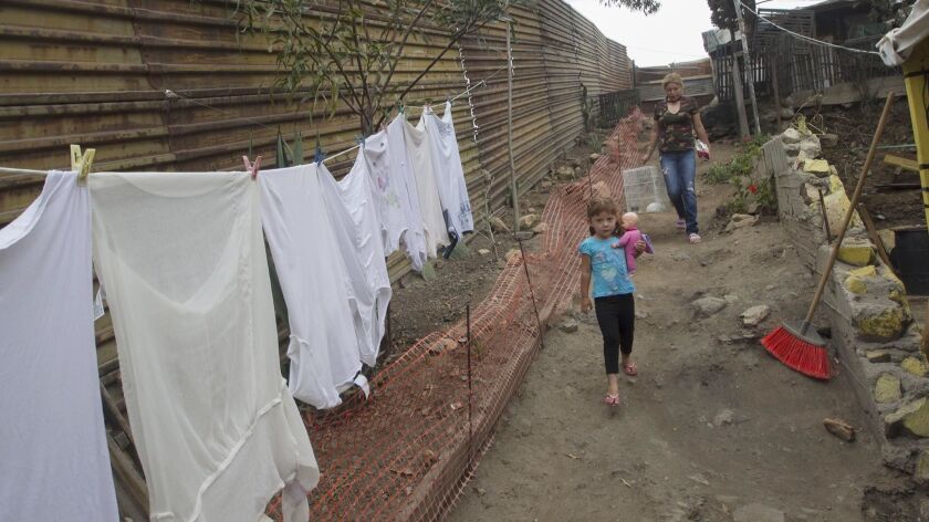 Cinthia Soto Esparza and her three-year-old daughter Brittany walk down the path in their enclosed property that has the U.S. border fence as their northernmost wall in the Nido de las Aquilas section of Tijuana.