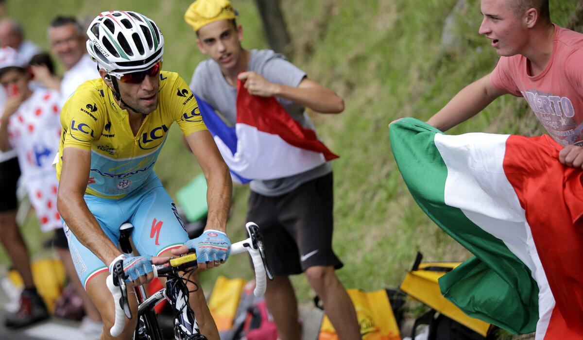 A fan (right) waves an Italian flag as stage winner and overall leader Vincenzo Nibali climbs toward Hautacam during the eighteenth stage of the Tour de France on Thursday.