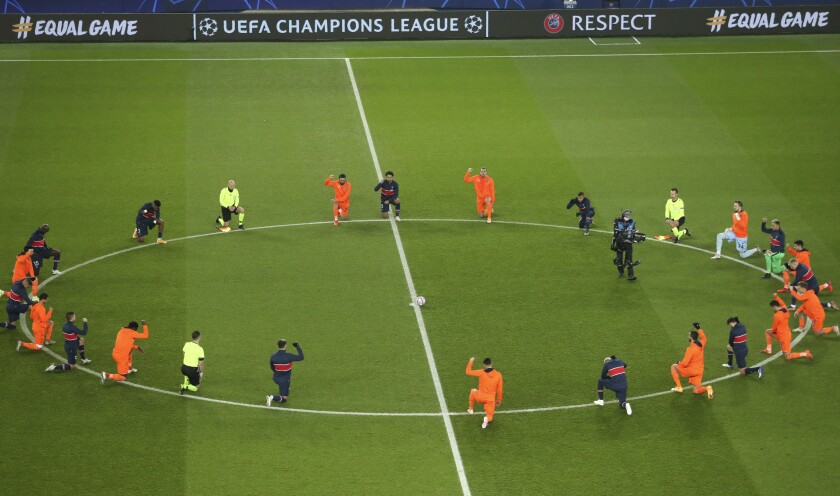 Basaksehir players kneel in support of the Black Lives Matter campaign before the start of the Champions League group H soccer match between Paris Saint Germain and Istanbul Basaksehir at the Parc des Princes stadium in Paris, France, Wednesday, Dec. 9, 2020. The match is resuming on Wednesday with a new refereeing team after players from Paris Saint-Germain and Istanbul Basaksehir left the field on Tuesday evening and didn't return when the fourth official — Sebastian Coltescu of Romania — was accused of using a racial term to identify Basaksehir assistant coach Pierre Webo before sending him off for his conduct on the sidelines. (Xavier Laine/Pool via AP)