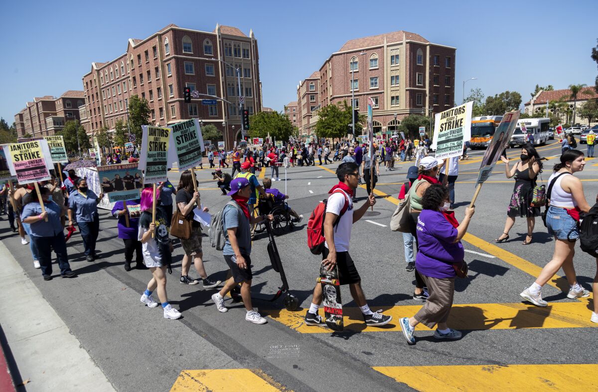 People march on a campus while holding signs