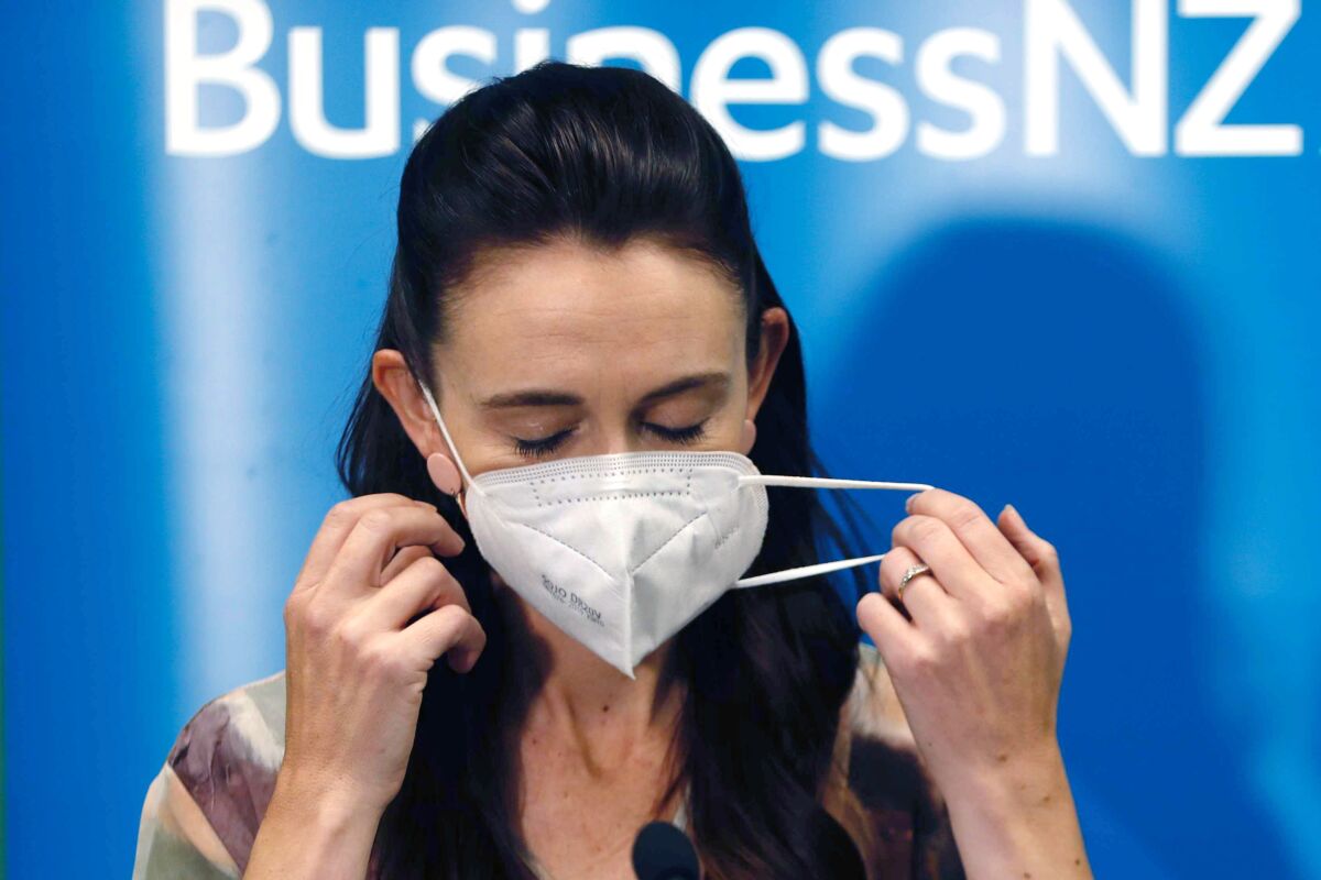 New Zealand Prime Minister Jacinda Ardern removes her mask before she outlines the Government's plans, Thursday, Feb. 3, 2022, that will dismantle its quarantine system and reopen its borders the world. Since the start of the pandemic, New Zealand has enacted some of the world's strictest border controls. (Dean Purcell/New Zealand Herald via AP)