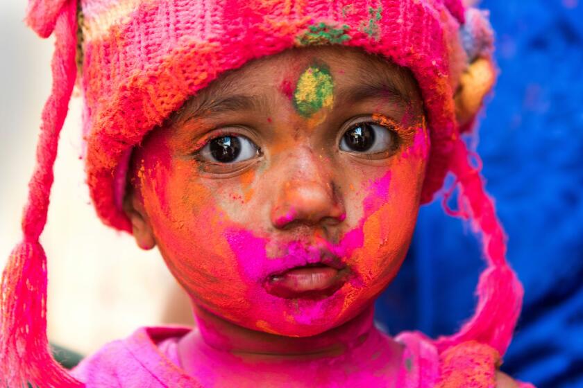 A young Indian reveller covered in coloured powder poses during the Holi Festival in Jaisalmer.