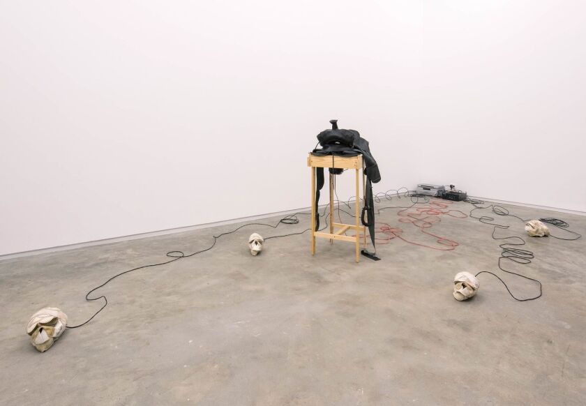 A gallery features skulls made from worn softballs connected by wires to a wooden plinth
