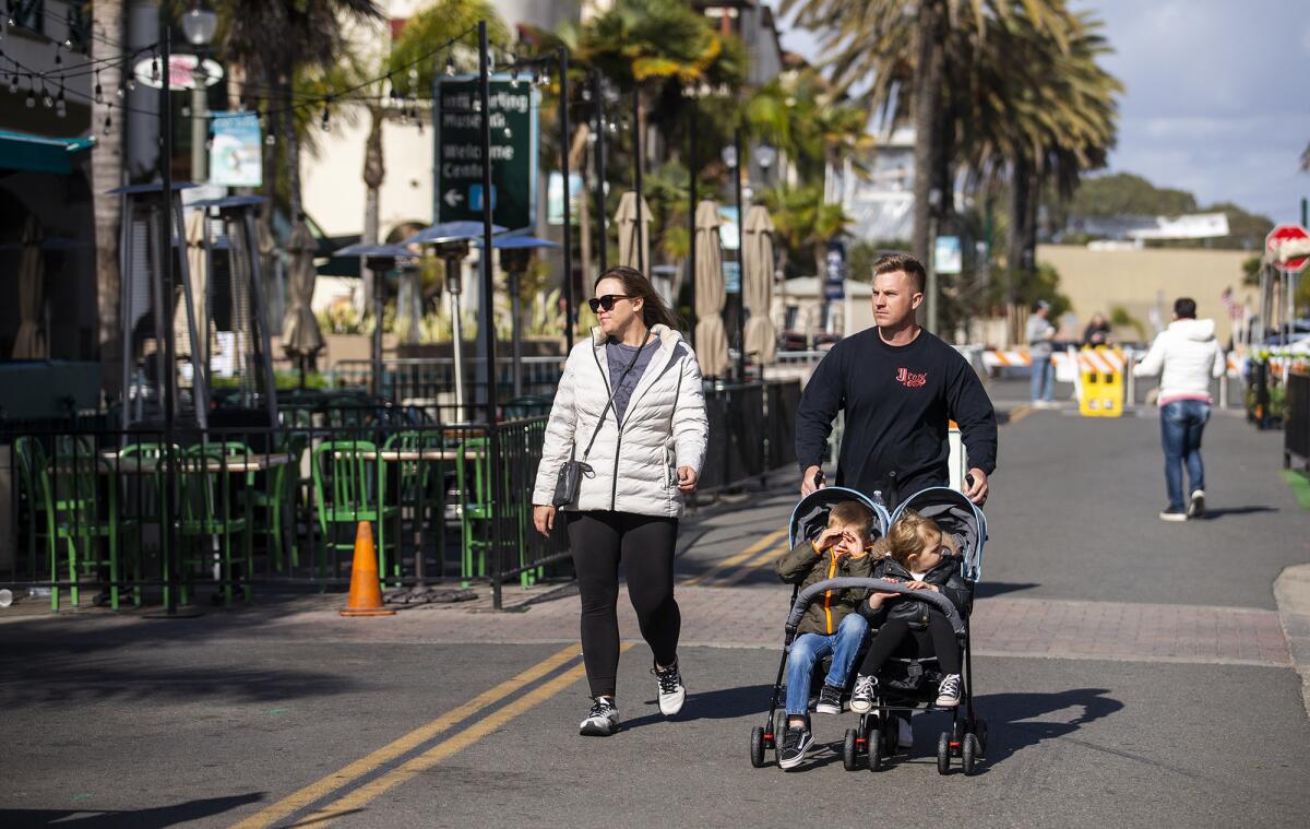 A family walks down Main Street in Huntington Beach on Monday, March 15.