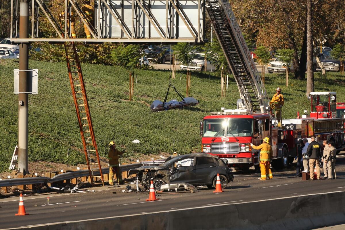 Firefighters use a ladder truck to remove the body of a 20-year-old man whose body landed on a freeway sign after he was ejected from a vehicle during a crash in Glendale on Oct 30.