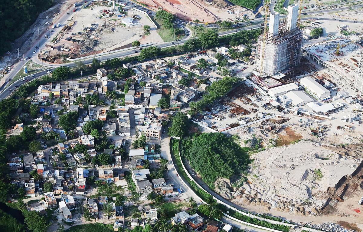 Construction continues at the Olympic Park for the Rio 2016 Olympic Games in the Barra da Tijuca neighborhood, as remaining homes from the Vila Autodromo 'favela' stand on February 24, 2015 in Rio de Janeiro, Brazil. Around 500 families originally lived in the community which started as a fishermen's village. The government tore down most of the homes but says it is rebuilding homes for the twenty or so families that fought to remain.