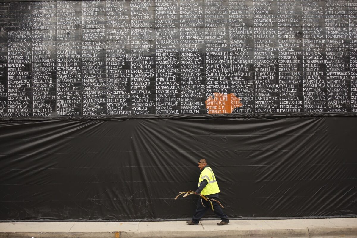 A man walks past the Vietnam veterans mural, which was covered with plastic after it was vandalized just before Memorial Day.