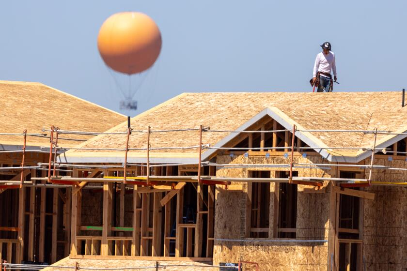 Irvine, CA - September 05: A construction worker works on the roof of new homes amidst a heat wave as the Great Park Balloon Ride rises in the horizon in Irvine Thursday, Sept. 5, 2024. (Allen J. Schaben / Los Angeles Times)