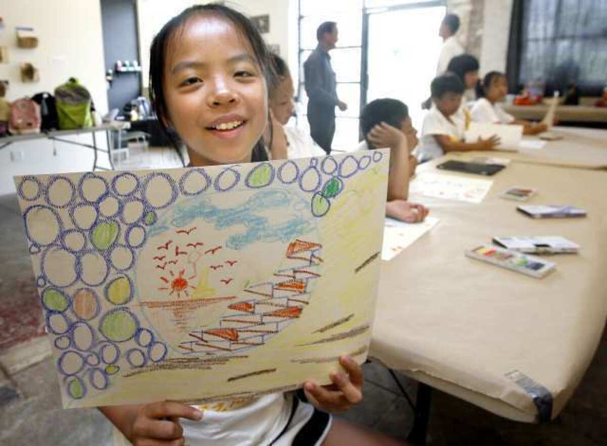 Chinese art student Bailli Zou, 11, left, shows her oil pastels artwork made during visit to the Armory Center for the Arts in Pasadena.