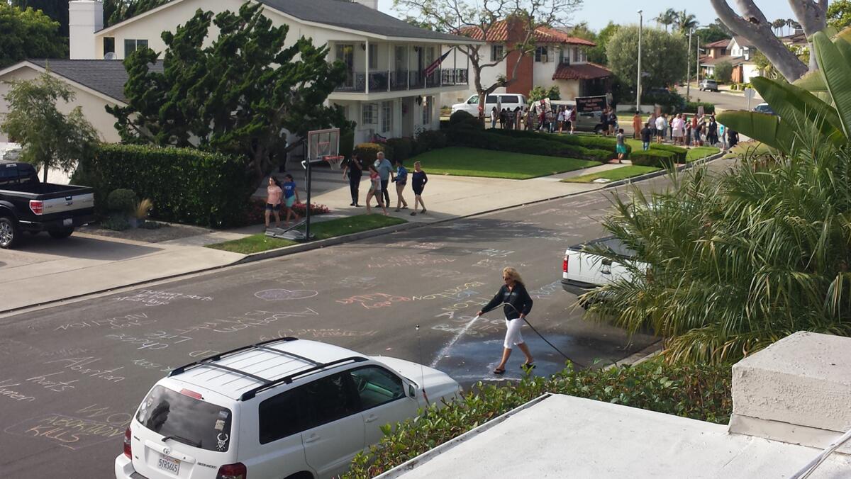 Paula Durnian hoses off anti-abortion messages written in chalk on the street in Newport Beach. Twice in the past week, pro-life protestors allegedly left messages targeting Durnian's neighbor, Dr. Richard Agnew, an OBGYN.