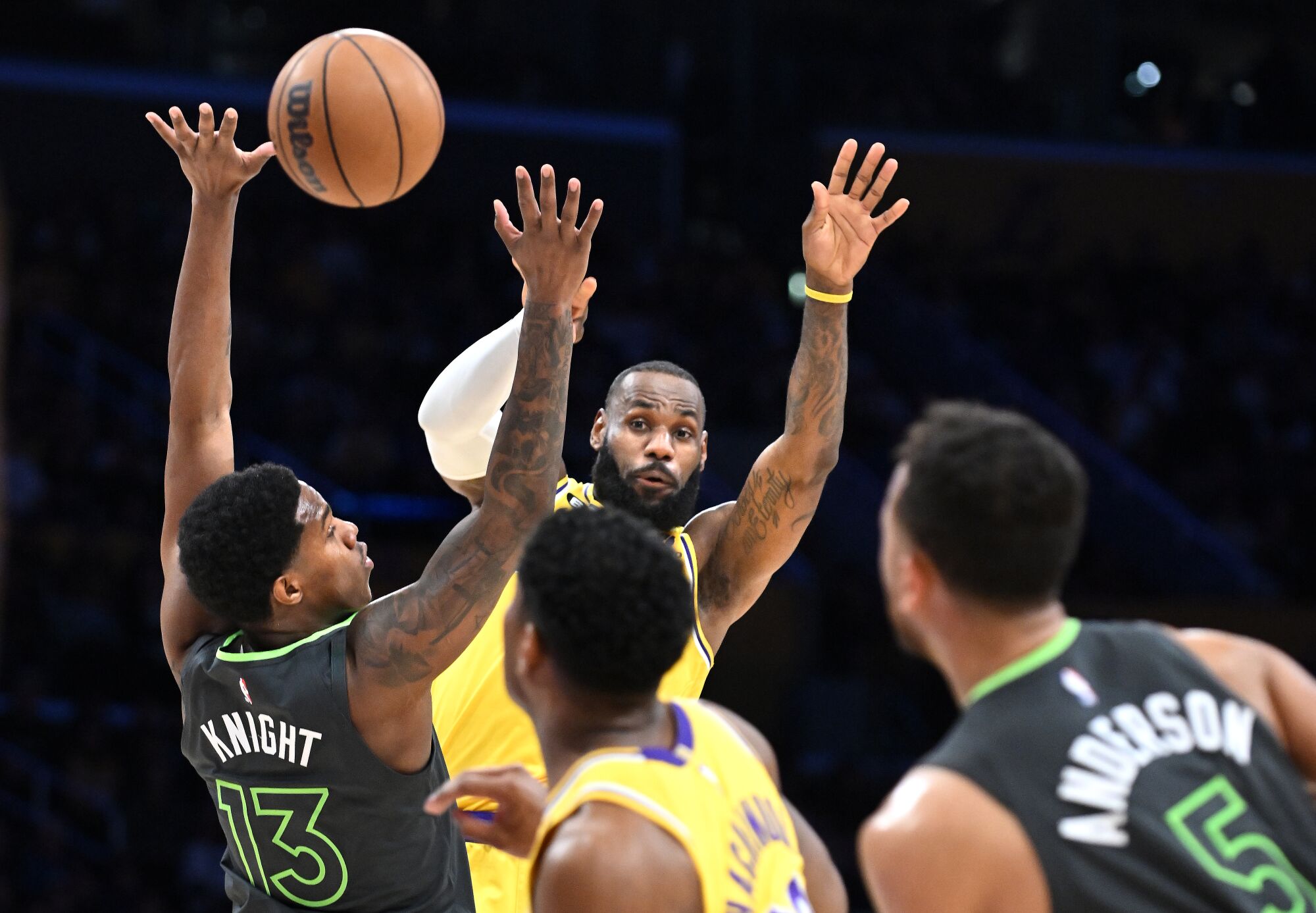 L'attaquant des Lakers LeBron James passe le ballon au-dessus d'un défenseur des Timberwolves à un coéquipier coupant au panier.