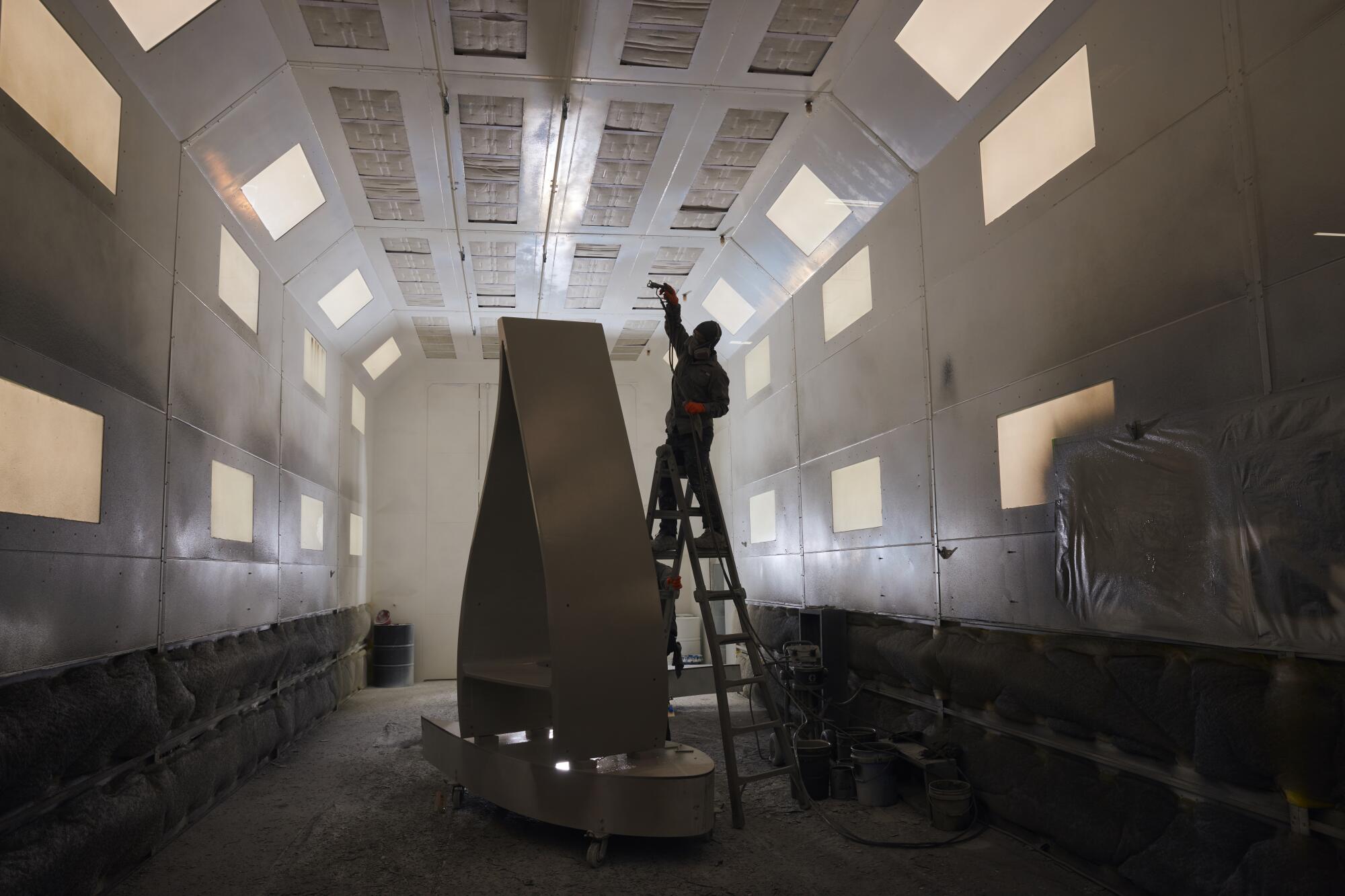 A worker applies paint to a section of a decommissioned wind turbine blade.