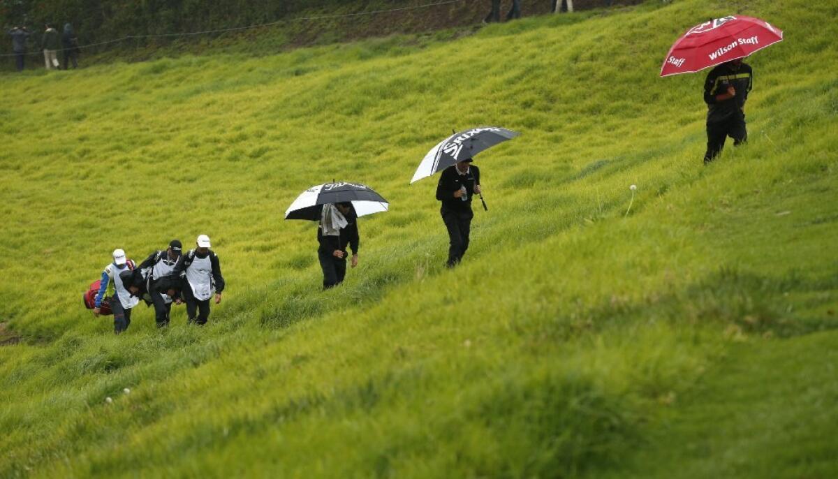 Golfers take cover from the rain during the second round of the Genesis Open at the Riviera Country Club on Feb. 17.