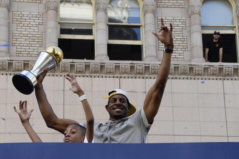 Golden State Warriors player and NBA Finals MVP Andre Iguodala holds up the trophy while acknowledging the crowd during the Warriors 2015 NBA Championship Parade and Rally in downtown Oakland.