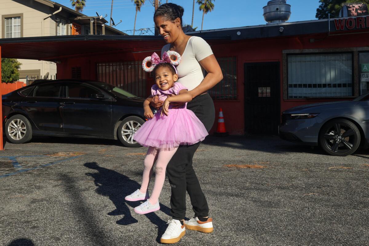 Porsha Scott cradles her daughter Amil Flowers, 2, as they wait for their order in the parking lot.