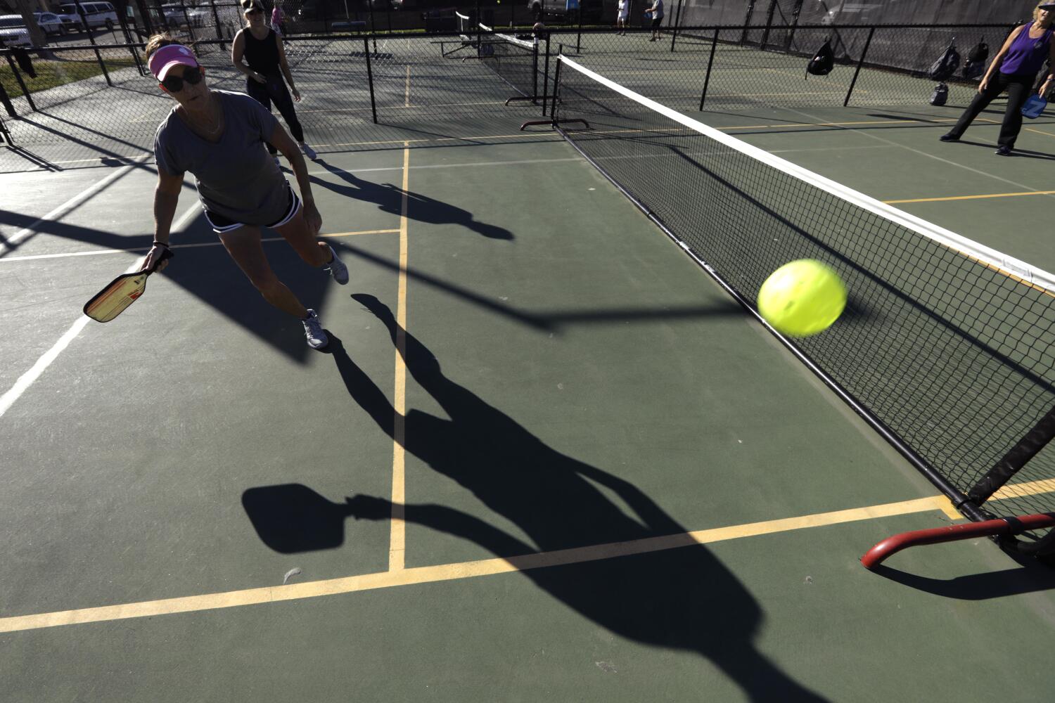 GOLETA, CA - FEBRUARY 18, 2022 - - Lisa Streett goes after a ball while playing a game of pickleball at the Goleta Valley Community Center in Goleta on February 18, 2022. Pickleball is a paddleball sport that combines elements of badminton, table tennis, and tennis. Two or four players use solid paddles made of wood or composite materials to hit a perforated polymer ball, much like a wiffle ball, with 26-40 round holes, over a net. Communities are beginning to sue to keep pickleball off tennis courts, tennis players hate them and HOA's are starting to ban them. (Genaro Molina / Los Angeles Times)