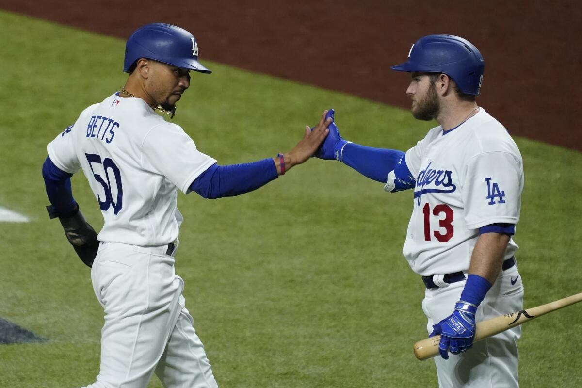 Mookie Betts, left, celebrates with Max Muncy after scoring a run during the sixth inning for the Dodgers on Tuesday.