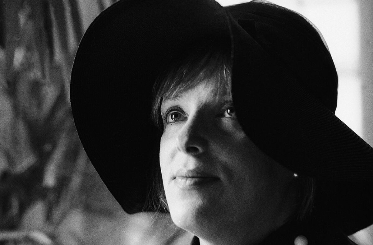 A black and white photo of a woman wearing a black floppy hat.