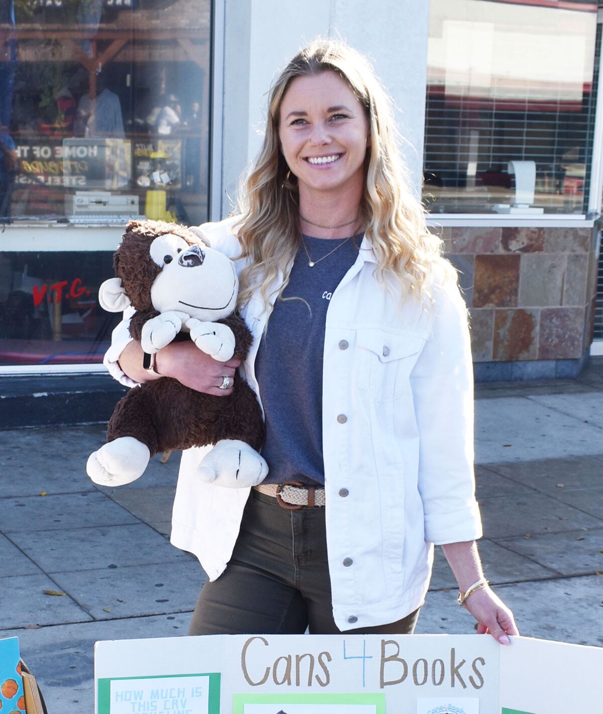 Pacific Beach resident Trisha Goolsby holding stuffed monkey Rupert, one of the Cans4Books mascots.