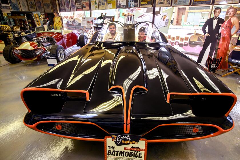 NORTH HOLLYWOOD, CA -JULY 26, 2021: Jared Barris and his mother Joji Barris-Paster are photographed inside an exhibition replica of the Batmobile, on display inside the showroom at Barris Kustom Industries in North Hollywood. The Batmobile was designed exclusively for the 1966 TV show, "Batman," by the late George Barris, Jared's grandfather, and Joji's father. Barris Kustom Industries is being listed for sale. (Mel Melcon / Los Angeles Times)