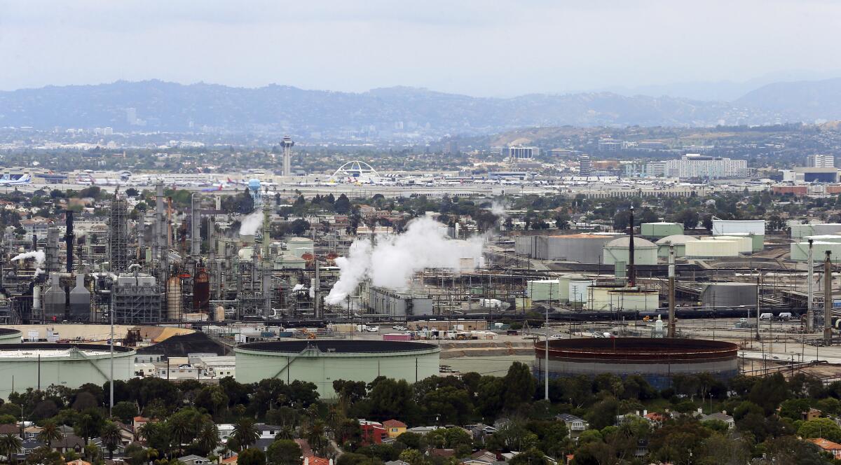 An aerial view of an oil refinery, foreground, with LAX and its Theme Building in the background