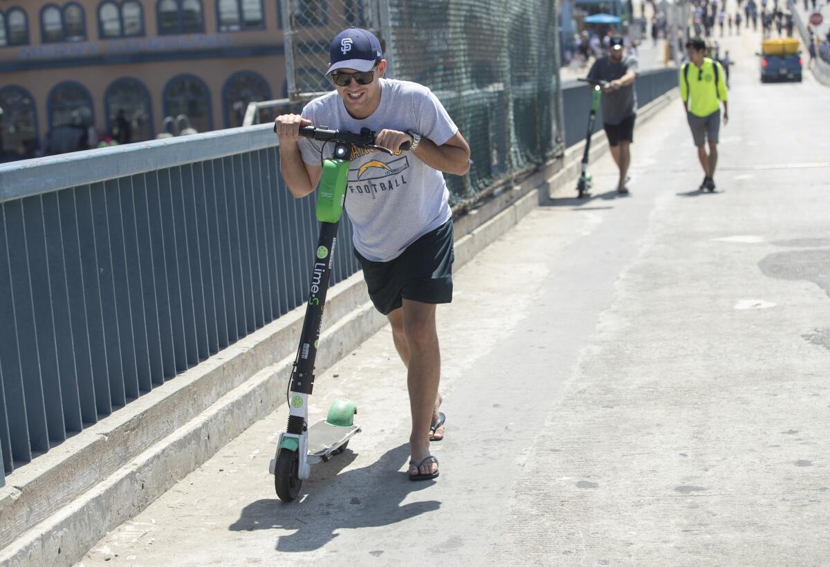 Elliot Stevenson pushes his Lime scooter up the hill from the Santa Monica Pier after a geofence disabled it. 