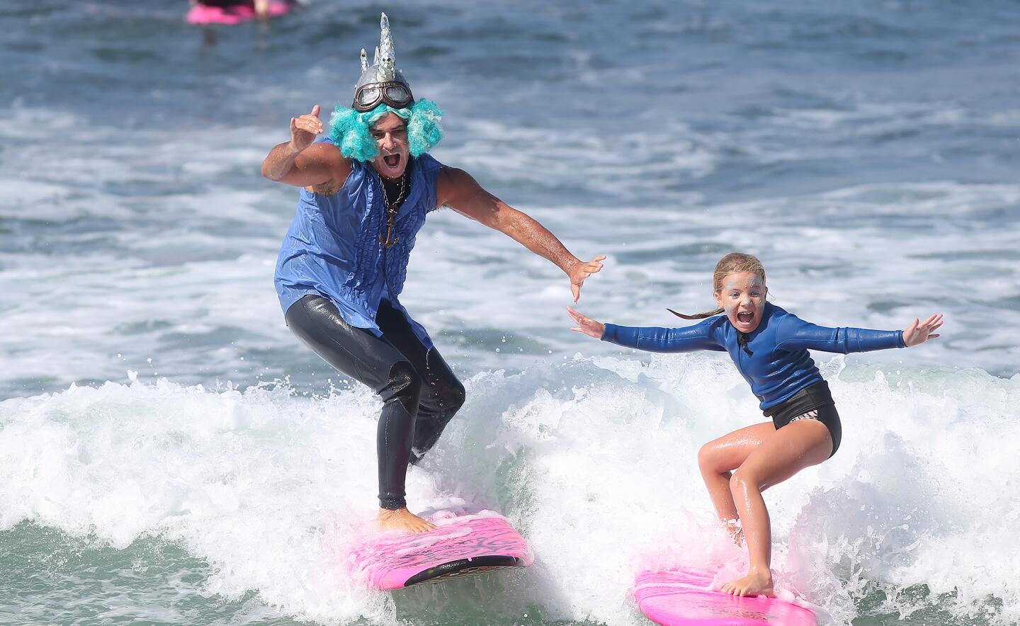 Dressed as a viking, instructor Steven "SLi Dawg" Chew, left, surfs Friday with a youngster in the Laguna Beach Surf School summer camp in Laguna Beach.