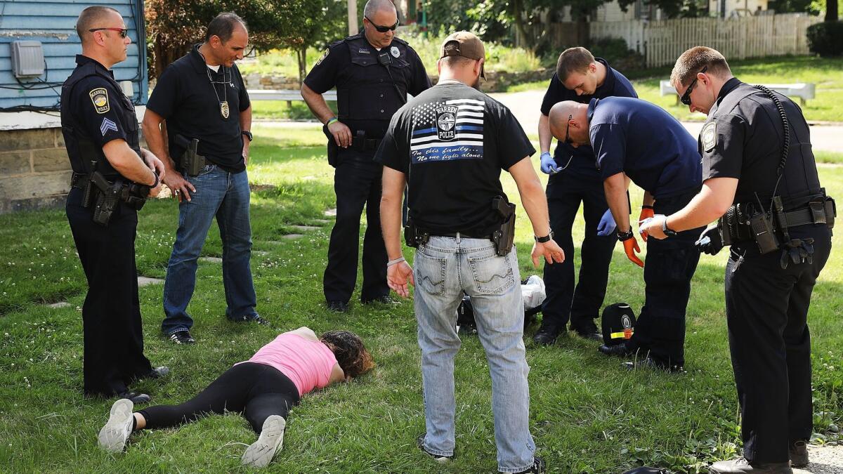 Medical workers and police treat a woman who has overdosed on opioids on July 14 in Warren, Ohio.