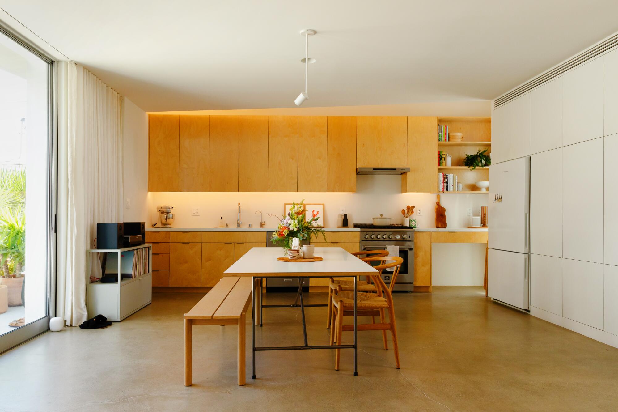A full-size kitchen with custom birch cabinets, a dining table and polished concrete floors.