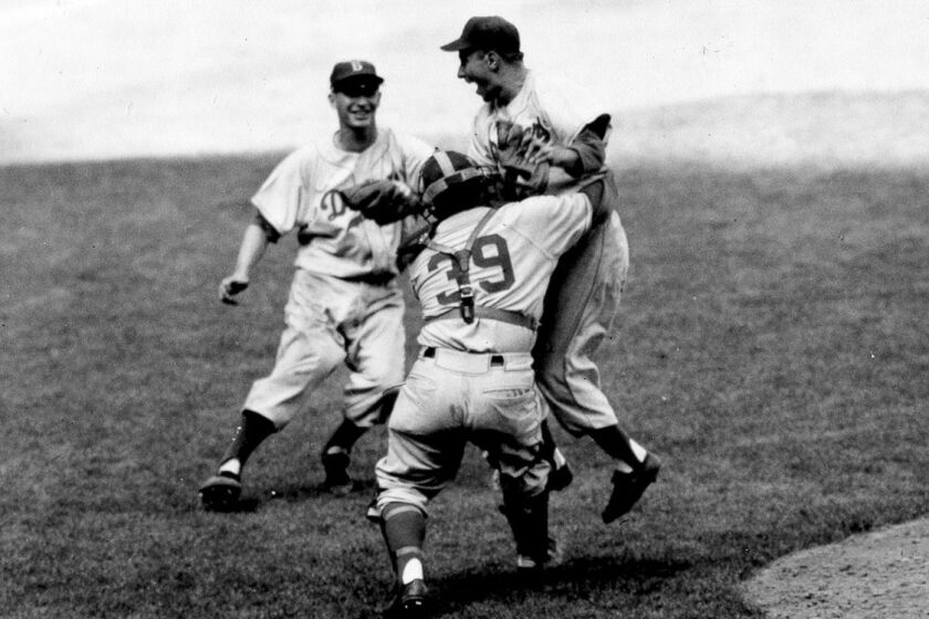 Brooklyn Dodgers pitcher Johnny Podres is lifted by catcher Roy Campanella after the final out.