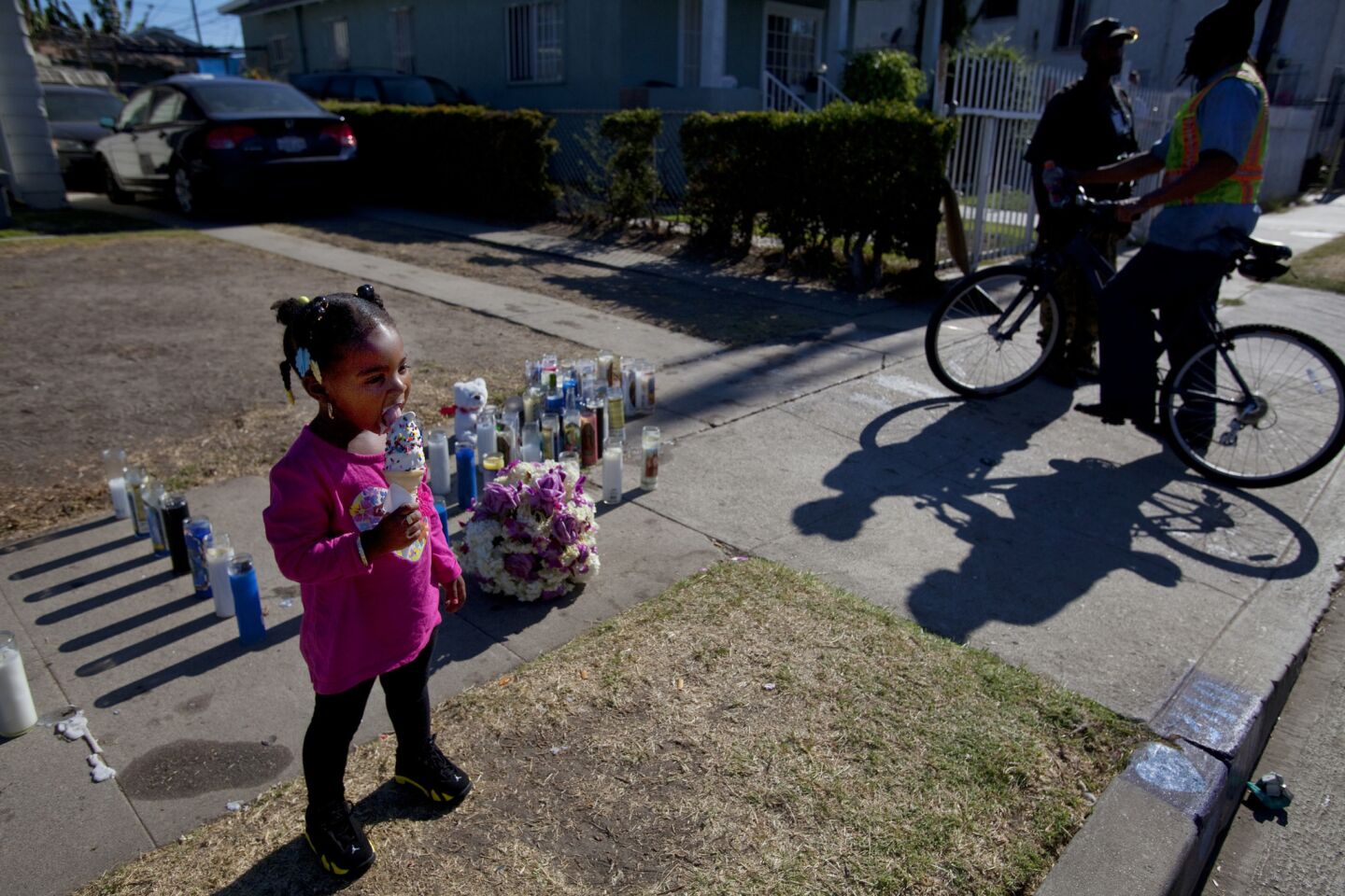 Aubriel Turner, 2, eats an ice cream cone Wednesday near candles placed on the sidewalk in remembrance of her cousin, Ezell Ford, who was killed by Los Angeles police officers in the 200 block of West 65th Street.