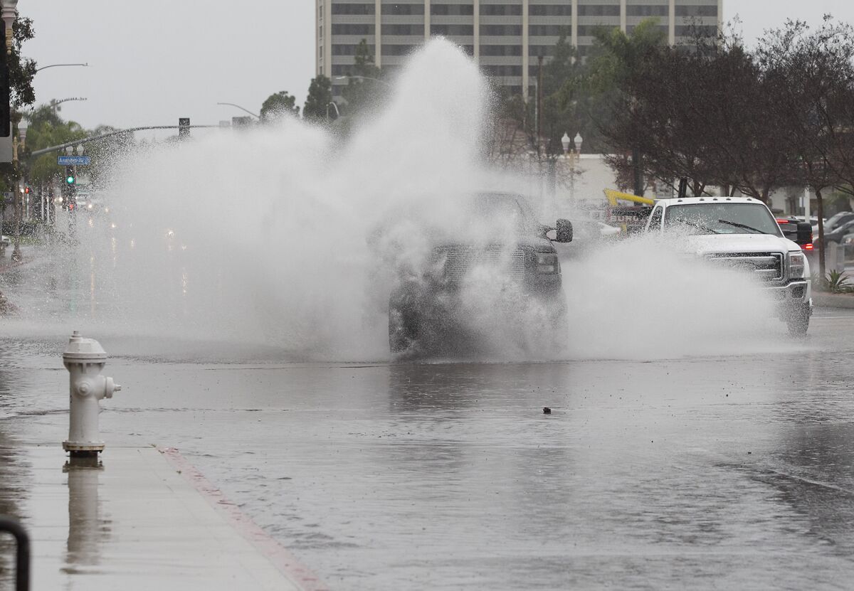 A truck plows through a flooded intersection on 19th Street in Costa Mesa after a storm.