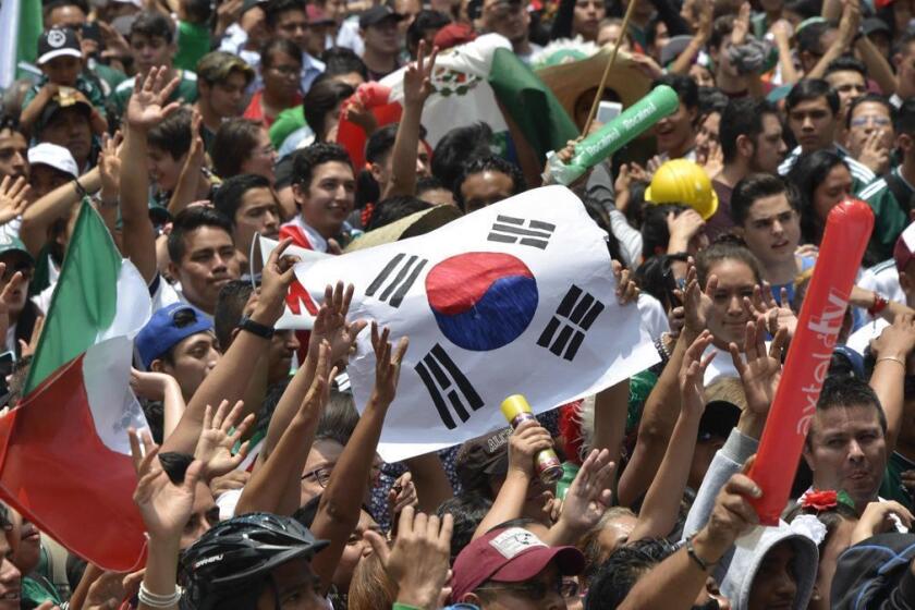 A football fan holds a flag of South Korea as thousands watch the World Cup match between Mexico and Sweden on a screen at the Angel de la Independencia Monument in Mexico City, on June 27, 2018. / AFP PHOTO / Johan ORDONEZJOHAN ORDONEZ/AFP/Getty Images ** OUTS - ELSENT, FPG, CM - OUTS * NM, PH, VA if sourced by CT, LA or MoD **
