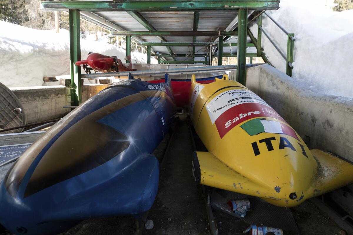 FILE - Bobsleds are parked next to the track in Cortina d'Ampezzo, Italy, on Feb. 17, 2021. Costly construction delays, a leadership vacancy linked to a volatile political climate and a lack of sponsors amid a spreading financial crisis has prompted International Olympic Committee president Thomas Bach to acknowledge the "challenges" facing organizers for the 2026 Winter Games in Milan and Cortina d'Ampezzo. (AP Photo/Gabriele Facciotti, File)
