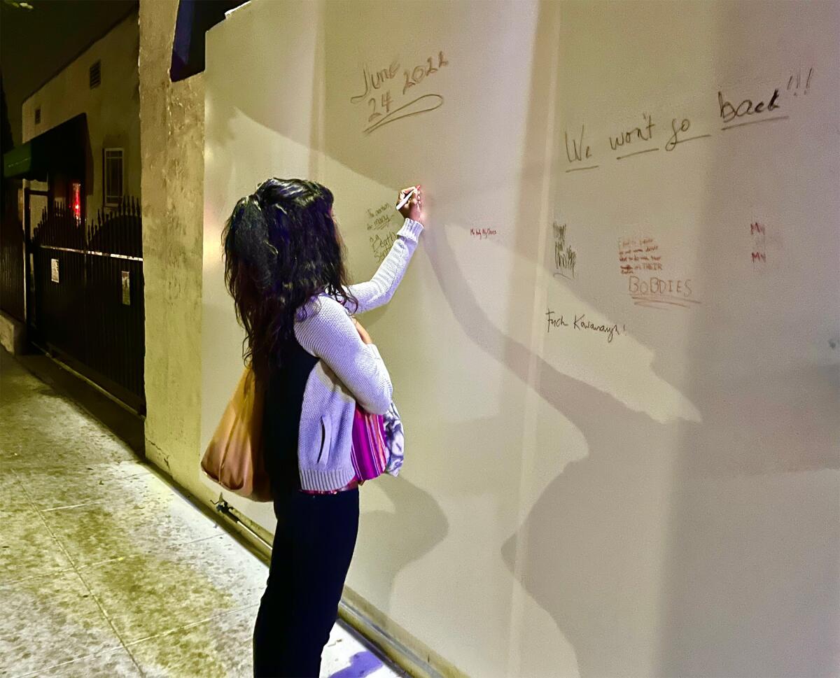 A woman writes on the Fountain Theatre's new memorial wall, created for public expressions of "grief and anger."