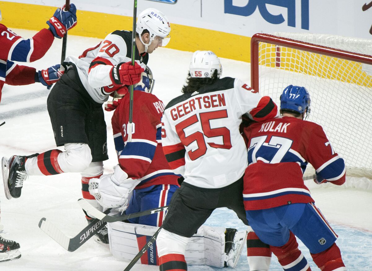 Montreal Canadiens goaltender Cayden Primeau is scored on by New Jersey Devils' Michael McLeod (20) as Devils' Mason Geertsen (55) and Canadiens' Brett Kulak (77) look on during the first period of an NHL hockey game in Montreal, Tuesday, Feb., 8, 2022. (Graham Hughes/The Canadian Press via AP)