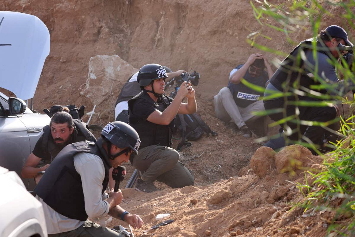Journalists in helmets crouching to take cover