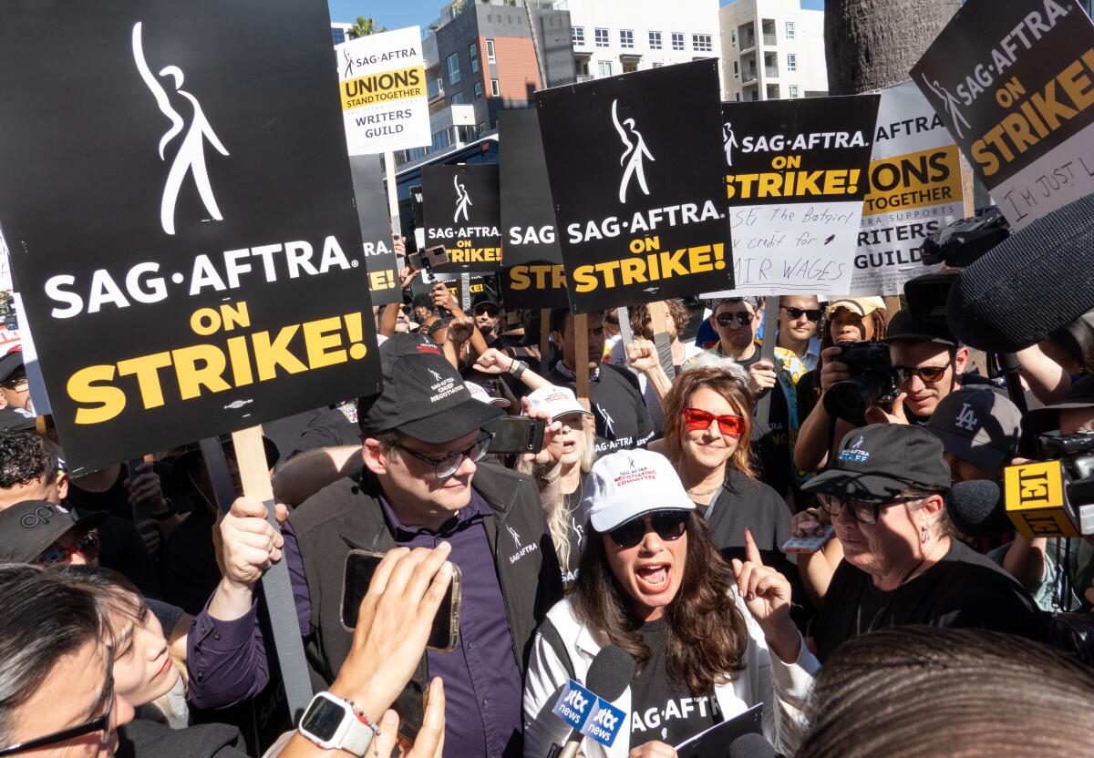 Sign-wielding striking actors gather on  a picket line.