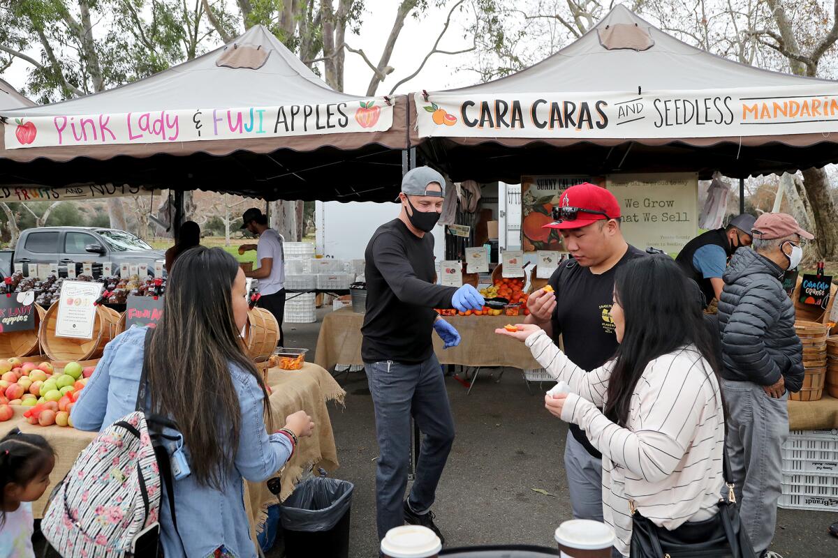 Sunny Cal Farms owner Shaun Rosendahl, center, hands out fruit samples to visitors.