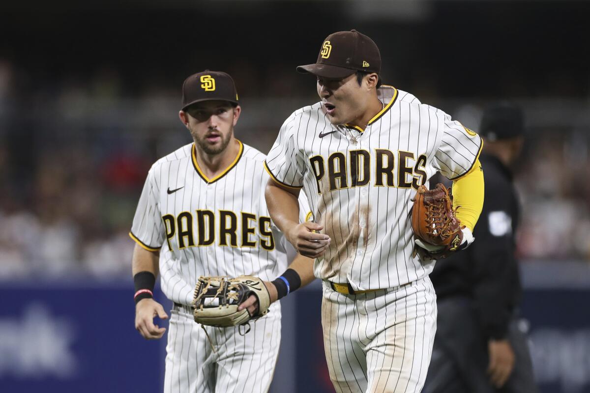 Padres shortstop Ha-Seong Kim, right, reacts after collision with Arizona's Alek Thomas as Matthew Batten looks on.