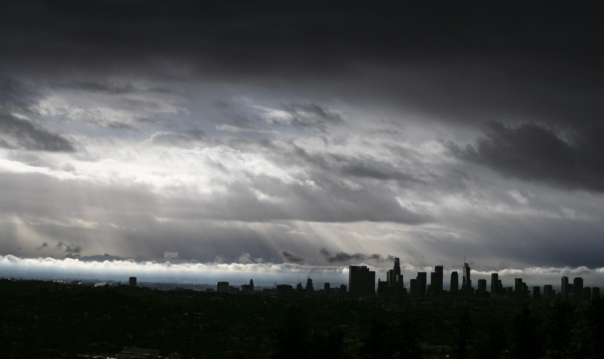 Dark clouds drift over the Los Angeles skyline.