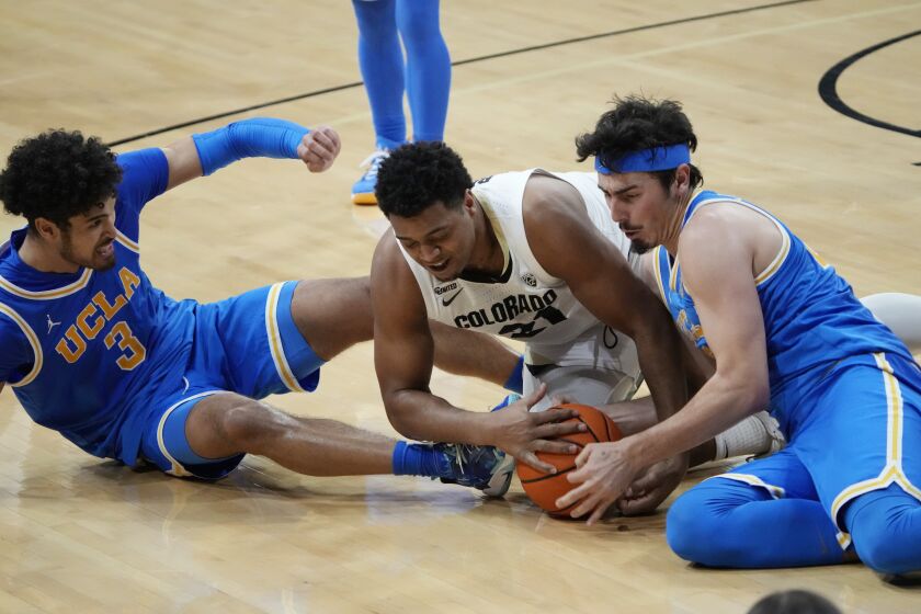 Colorado forward Evan Battey, center, fights for control of the ball against UCLA guards Jaime Jaquez Jr., right, and Johnny Juzang during the second half of an NCAA college basketball game Saturday, Jan. 22, 2022, in Boulder, Colo. UCLA won 71-65. (AP Photo/David Zalubowski)